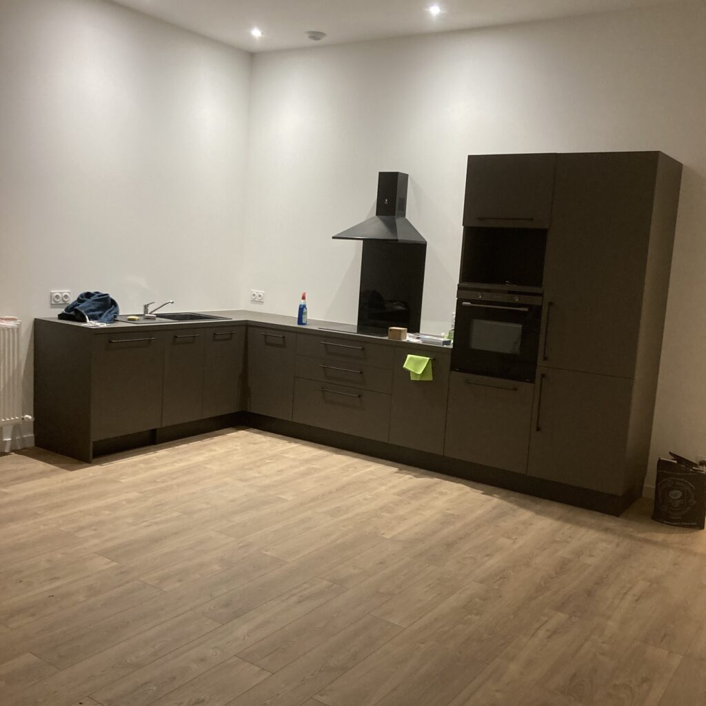 Cuisine aménagée après rénovation avec meubles et sol stratifié