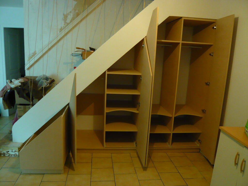 Aménagement intérieur du placard sous escalier avec étagères et penderies