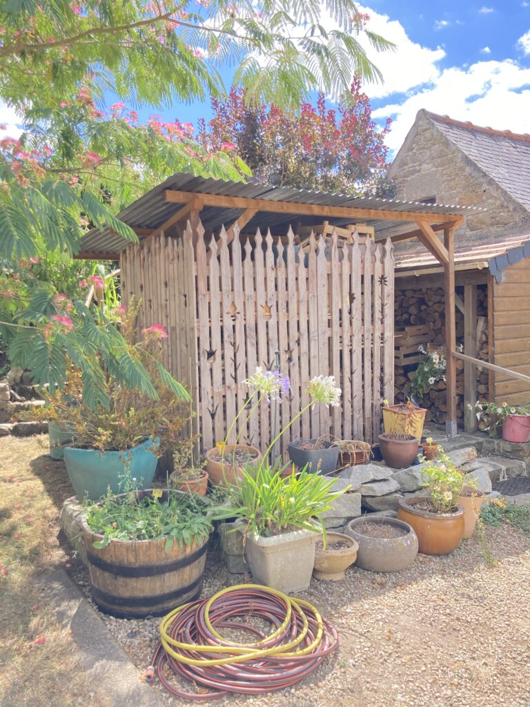 Petit abri à bois réalisé en réemploi avec bois de palettes et matériaux récupérés