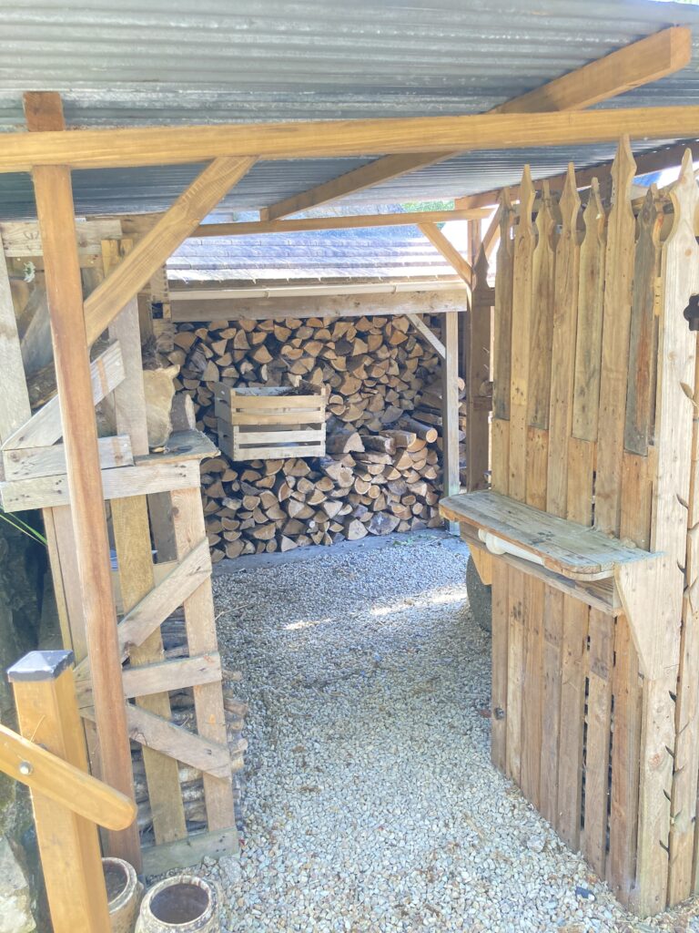 Intérieur d’un petit abri à bois aménagé avec des matériaux récupérés